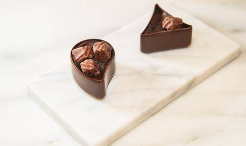 Two Mona Lisa chocolate bonbon cups resting on a piece of white marble with Gertrude Hawk Ingredients on top