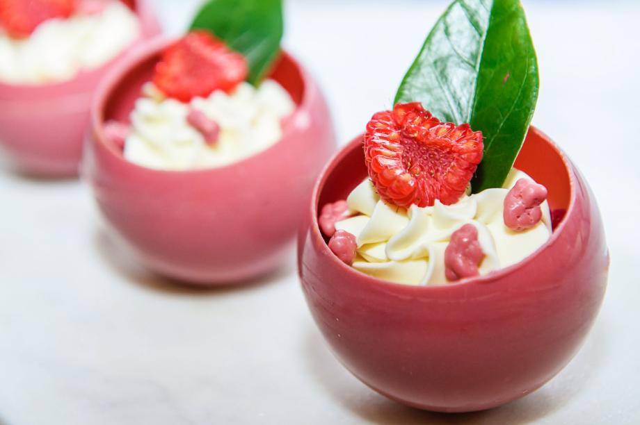 A beautiful spherical creation made using ruby and Mona Lisa Couverture Decorations, garnished with fresh raspberry and Ruby Biscottino